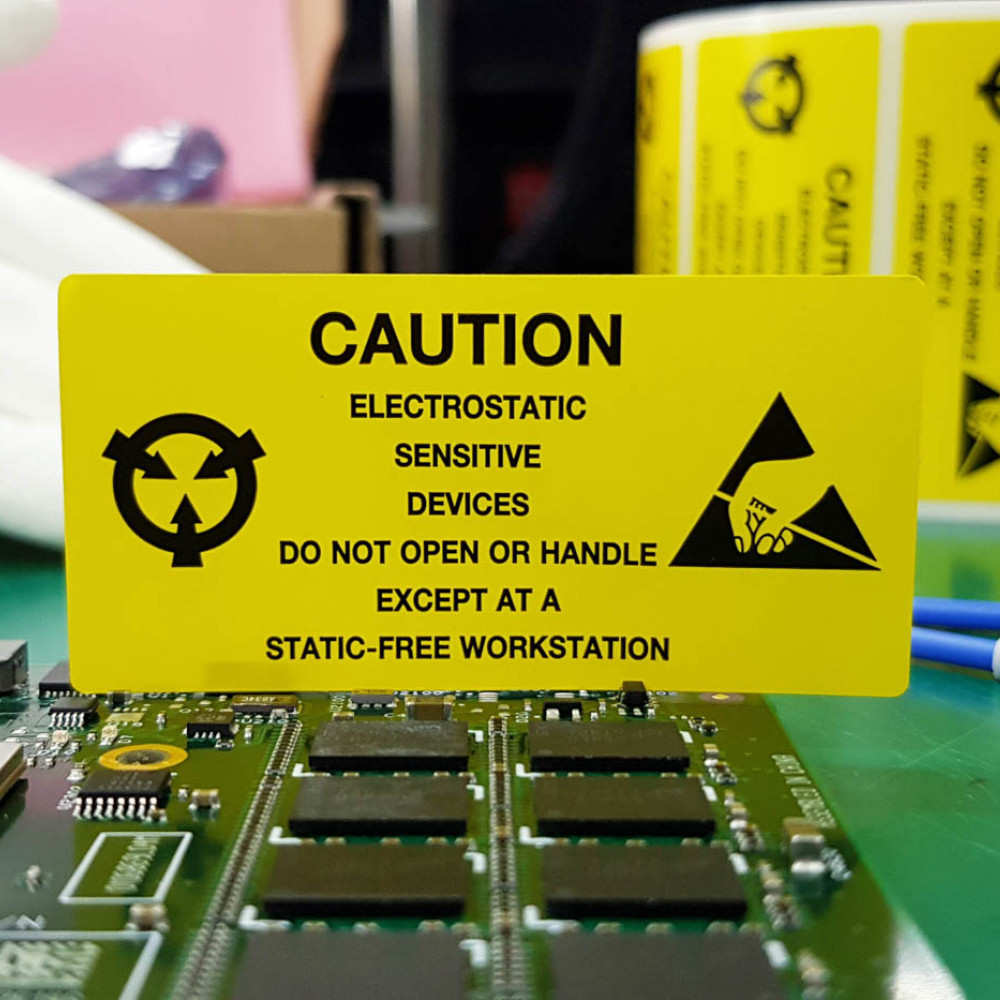 Ein gelbes Schild auf einer Leiterplatte weist auf ein ESD-empfindliches Gerät hin.